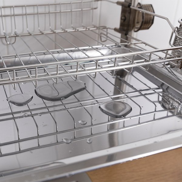 Clean dishes drying on metal dish rack on light background. Kitchen utensils and dishware on wooden shelf. Kitchen interior background.Text space.